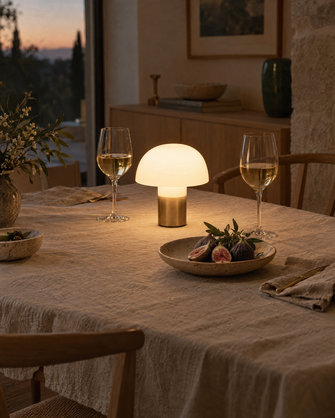 Cordless table lamp glowing on a dining table set for an evening dinner